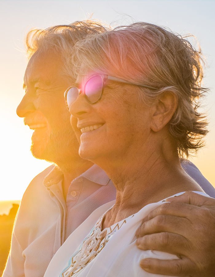 smiling elderly couple enjoying the sunset