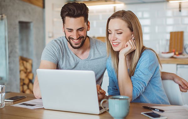 smiling young couple in front of a laptop